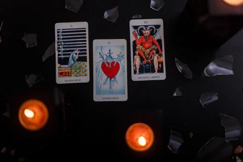 Divination cards alignment. Devil and swords. Black background with candles Stock Photos