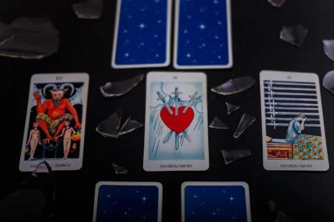 Divination cards alignment. Devil and swords. Black background, broken glass Stock Photos
