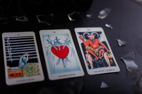 Divination cards alignment. Devil and swords. Black background, broken glass Stock Photos