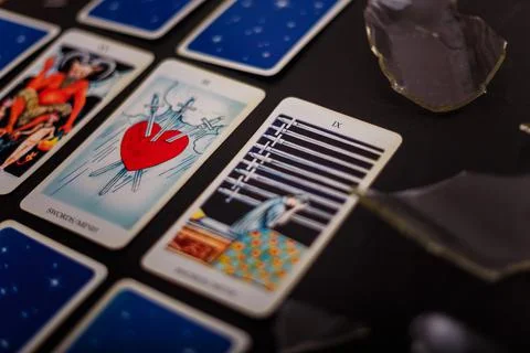 Divination cards alignment. Devil and swords. Black background, broken glass Stock Photos