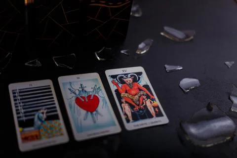 Divination cards alignment. Devil and swords. Black background, broken glass Stock Photos