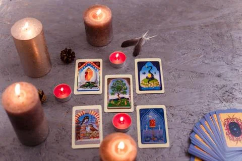 Divination cards alignment with feathers and candles on silver background. Stock Photos