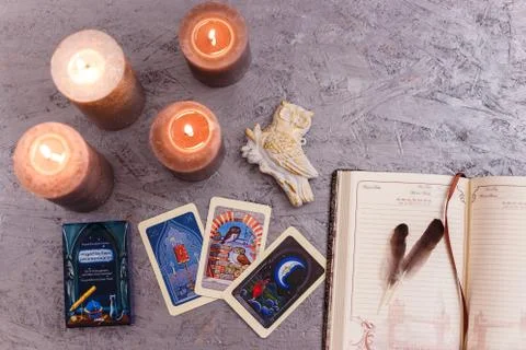Divination cards alignment with feathers and candles on silver background. Stock Photos