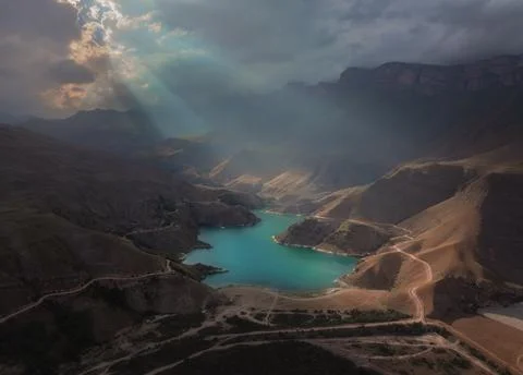 Divine sunlight falls through the clouds onto a beautiful lake in the mountains. Stock Photos