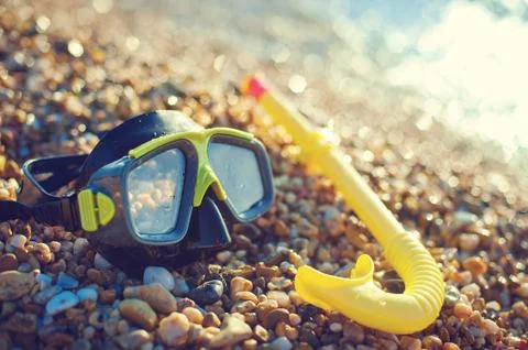 Diving concept - black mask and snorkel on Pebble beach Stock Photos