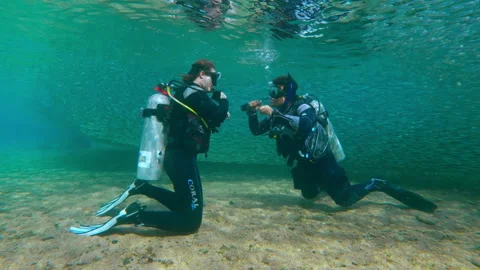 Diving instructor and entra diver prepare to submerge as solid wall of Stock Footage 337610044