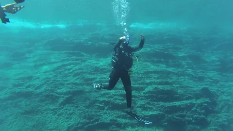 Diving instructor communicates vith other divers using gestures Stock Footage 79399717