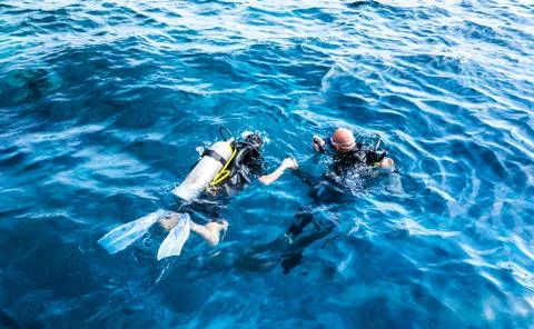 Diving instructor holding a disciple's hand in blue water Foto stock