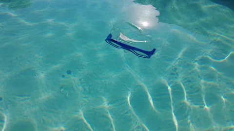 A diving mask floating on the surface of clear swimming pool water Stock Footage 245065606