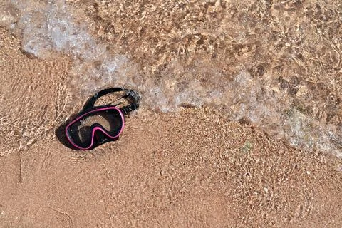 Diving mask on a sandy beach washed by water waves. Foto stock