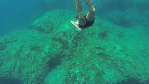 Diving, young man swims under water with eyes open and bright sunlight Stock Footage 104877522