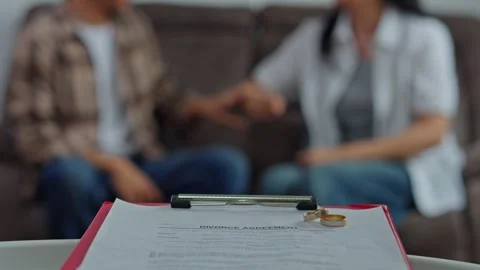 Divorce agreement on table with blurred couple in background Vidéo 331494034