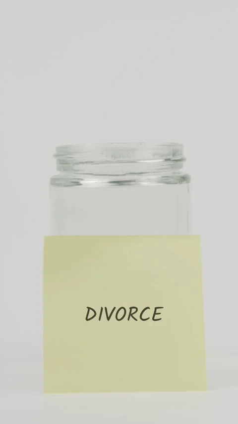 Divorce text or word on yellow sticky note attached to glass jar with hand Stock Footage 311720605