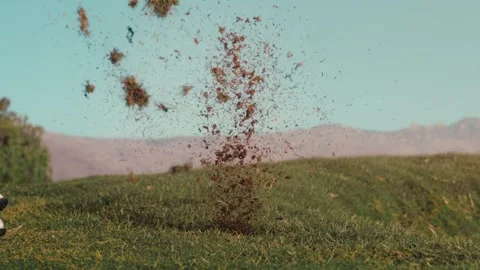 Divot exploding across the grass with a desert mountain backdrop in slow motion Stockbeeldmateriaal 340118263
