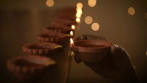 Diwali celebration Diya hand lighting up rows of Diya in close up a shallow Stock Footage