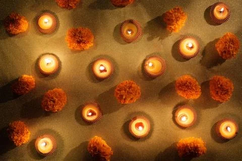 Diwali pattern with lit clay diyas and marigold flowers on golden background Stock Photos