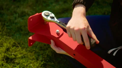 DIY builder adjusting socket wrench on metal frame joint in garden setting. Home Stock Footage 340196023