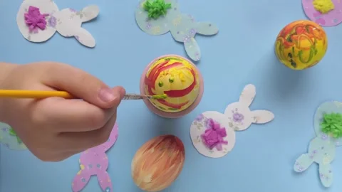 DIY Child decorating easter egg. Bunnies on blue background. Stock Footage 147357407
