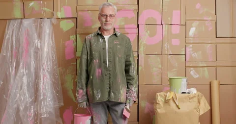 DIY concept. Serious grey haired senior man gives something lick holds paint Stock Footage 144918147