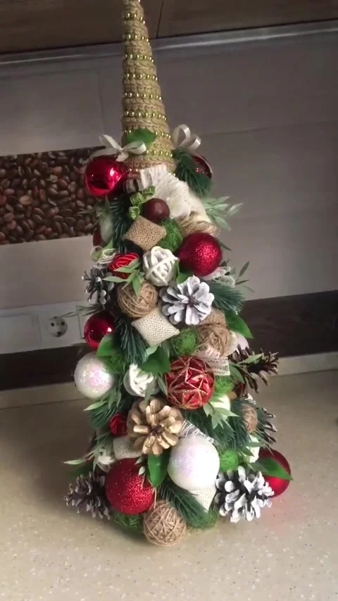 DIY decorated mini Christmas tree with ornaments and pinecones on table Vídeos de archivo 331198524