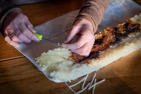 DIY, do it yourself. Two women's hands making a pillow using latchhooking Foto stock