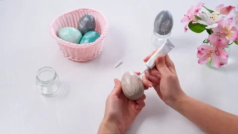 DIY Easter decor. Women's Hands paint Easter eggs and draw flowers pattern on Stock Footage 150137287