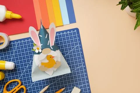 DIY Easter gnome with bunny ears and paper duck on blue background. Cutting.. Stock Photos