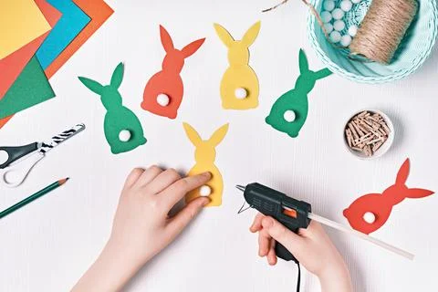 DIY Easter home decor from natural materials. Hands make garland of colored Stock Photos