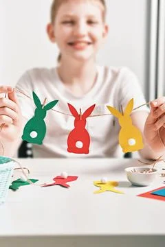 DIY Easter home decor from natural materials. Happy boy make garland of colored Stock Photos