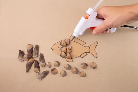 DIY fish shaped craft tutorial with pine cones seed scales, cardboard mater.. Stock Photos