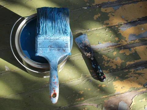 DIY home fixer upper concept with paint brush and can on peeling floor Stock Photos