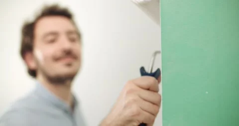 DIY Man paints a white wall at home with a roller Stock Footage 155796891