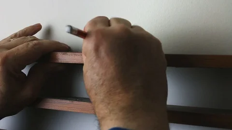 DIY man pencil marking position for hole in interior wall for cabinet mountin Video stock 123912455