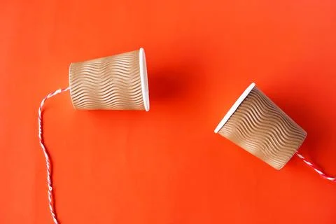 DIY paper cups with string on red background. Concept, telephone toy. Concept,  Stock Photos