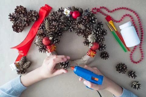 DIY. Step 2 top view of florist's hands, Christmas wreath of fir cones Stock Photos