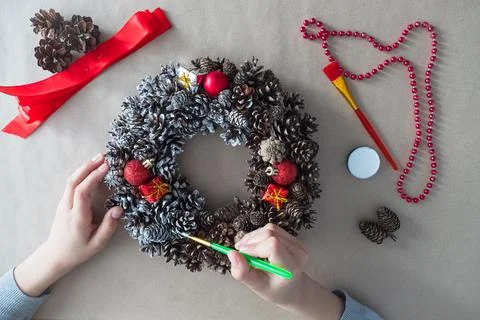 DIY. Step 3 top view of florist's hands with brush, Christmas wreath of fir Stock Photos