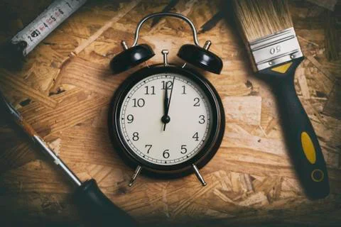 DIY time concept. Tools surrounding a black alarm clock. Stock Photos