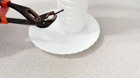 DIY Water Leak Hack: Piercing a Bottle Base with Screw Pliers Stock Footage 318579061