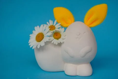 DIY white hare or rabbit with bright yellow ears and daisies on a blue backgr Stock Photos