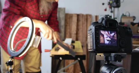 DIY woodworking vlogging, man cuts wood plank using japanese hand saw, filming Stock Footage 154856906