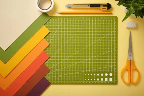 DIY workspace with cutting mat, scissors, knife, pencil, eraser, tape and p.. Stock Photos