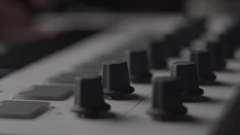 DJ adjusting audio effect knobs on MIDI keyboard while making music Stock Footage 108018342