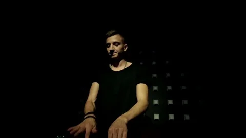 DJ behind the board is doing its job in the light of color music Stock Footage 73380093