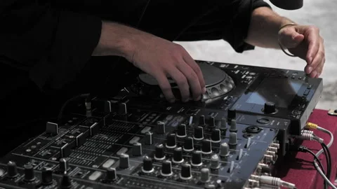 The DJ bends low to the console and mixes tracks with the DJ rig Stock Footage 172347980