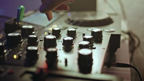 DJ hand tweaking knobs on mixer mixing music in clubbing scene closeup. 스톡 동영상 275206875