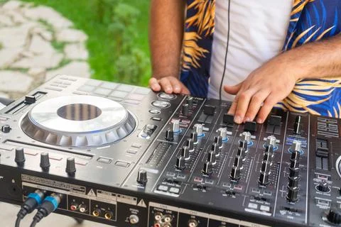 DJ Hands creating and regulating music on dj console mixer in concert party.. Stock Photos