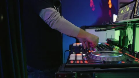 A DJ with his hands on a console touching knobs and faders at a club, 動画素材 167060876