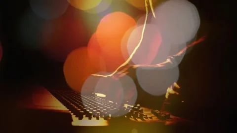 DJ leaning forward, adjusting mixer knobs and faders while mixing live set under Stock-Footage 333900924