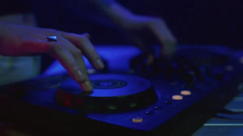 DJ mixes music using an audio mixer and turntables on stage. Knobs in hand 스톡 동영상 319040035