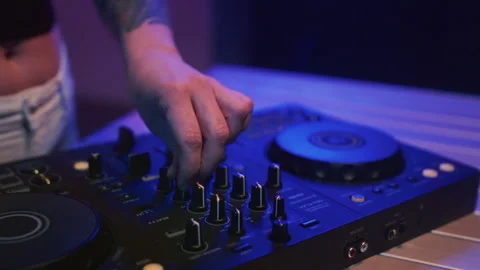 DJ mixes music using an audio mixer and turntables on stage. Knobs in hand Video stock 319762050